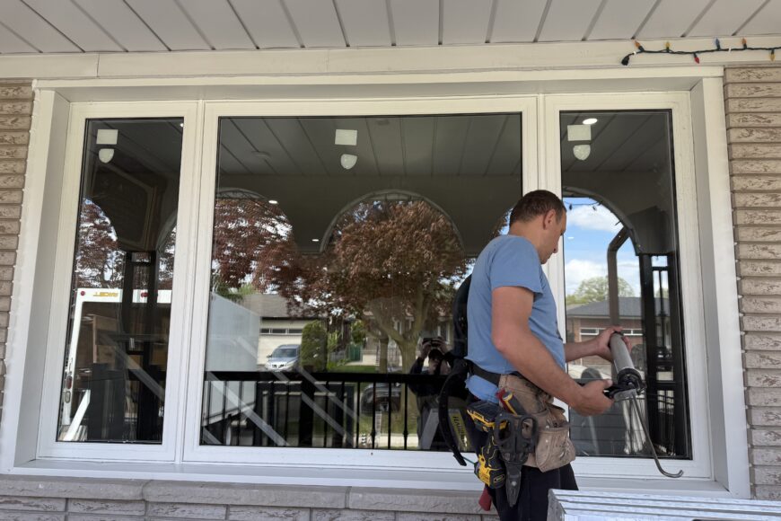 Installer sealing and finishing a replacement window during a window installation project in Barrie.
