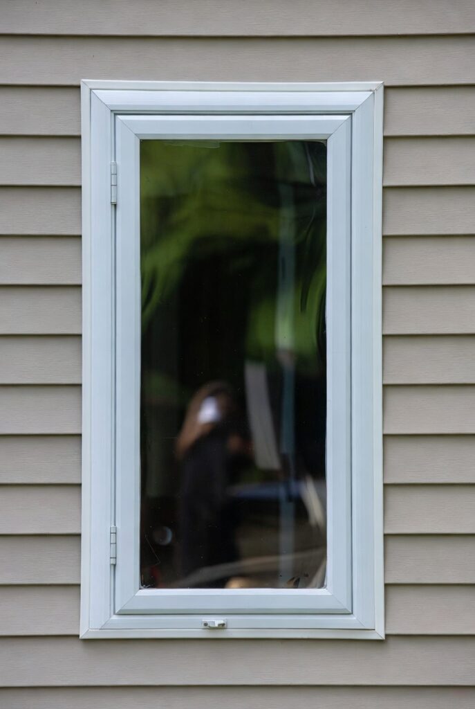 Closed operable casement window in a white vinyl frame.
